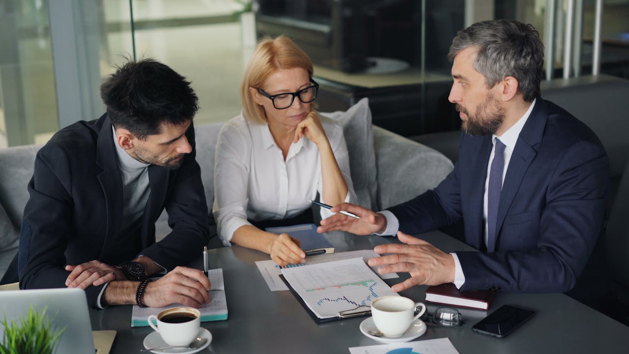 Three business people sitting at a table with a laptop